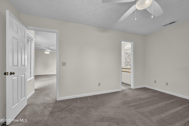unfurnished room with ceiling fan, visible vents, baseboards, and dark colored carpet