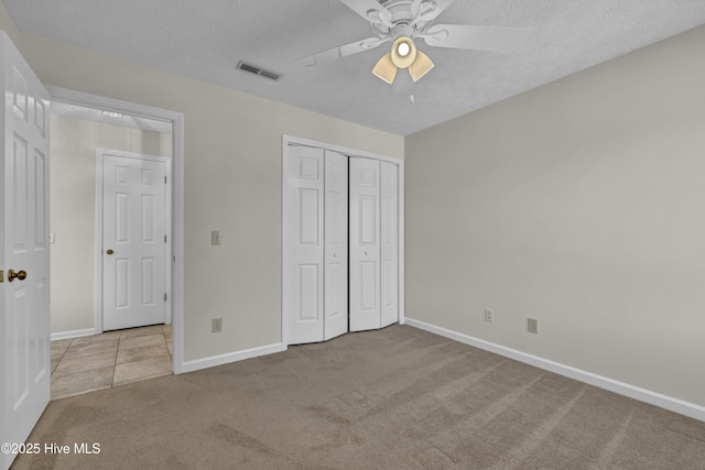 unfurnished bedroom with carpet floors, a textured ceiling, baseboards, visible vents, and a closet