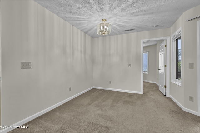 spare room featuring carpet floors, baseboards, a notable chandelier, and visible vents