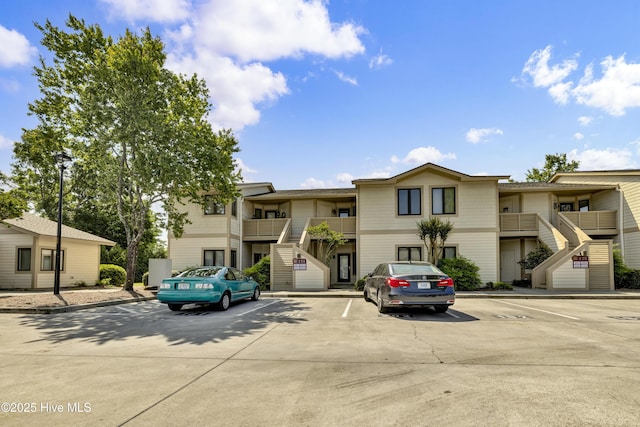 view of property with uncovered parking and stairs