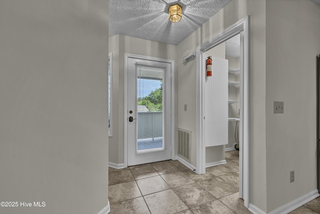 entryway with baseboards, tile patterned floors, and visible vents