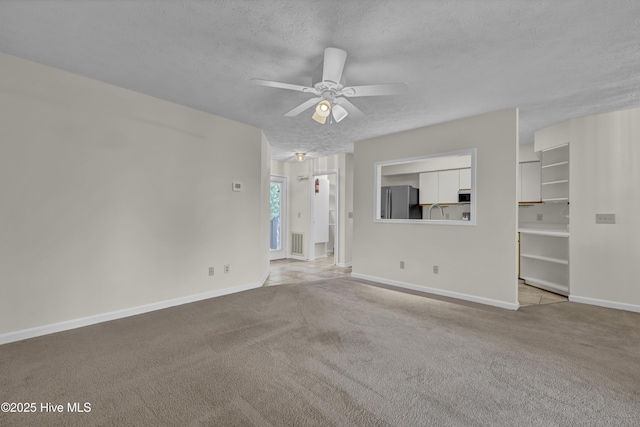 unfurnished living room with visible vents, baseboards, a textured ceiling, a ceiling fan, and carpet