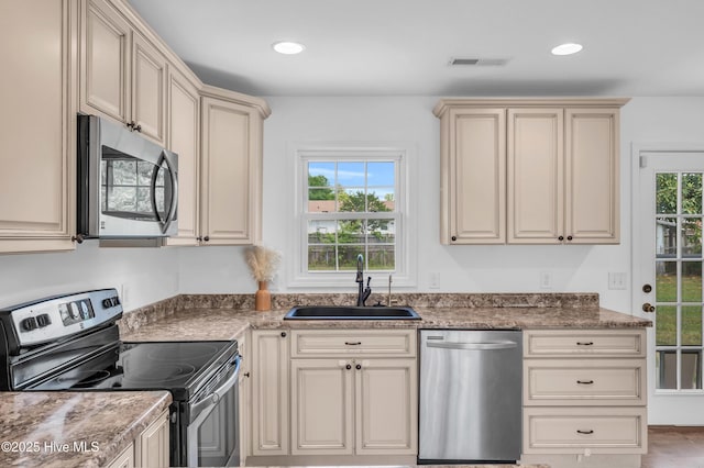 kitchen featuring cream cabinets, stainless steel appliances, a healthy amount of sunlight, and a sink