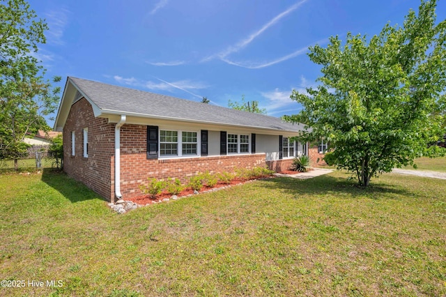 single story home featuring brick siding, a shingled roof, fence, and a front yard