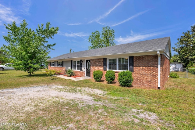 single story home featuring brick siding, fence, and a front yard