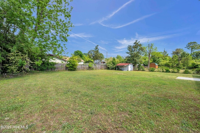 view of yard featuring fence, an outbuilding, and a storage unit