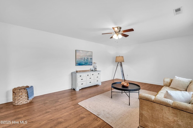 living area with a ceiling fan, baseboards, visible vents, and wood finished floors