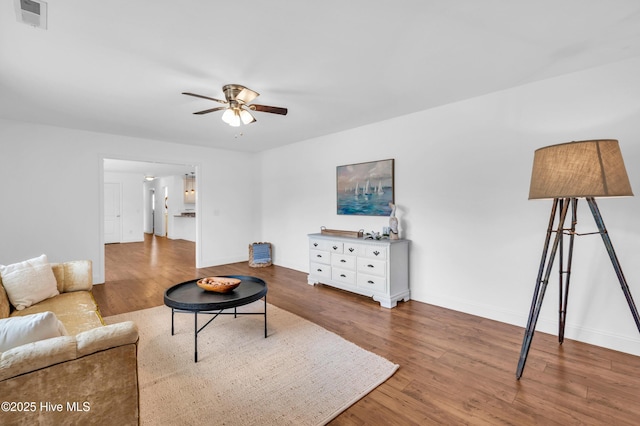 living room featuring a ceiling fan, baseboards, visible vents, and wood finished floors