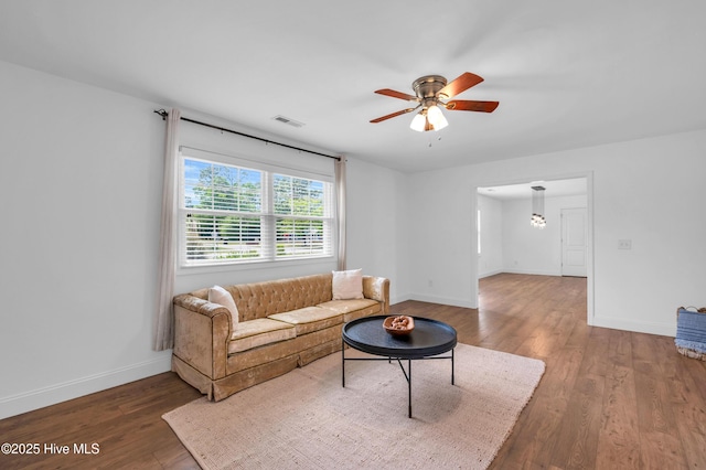 living room featuring visible vents, baseboards, ceiling fan with notable chandelier, and wood finished floors