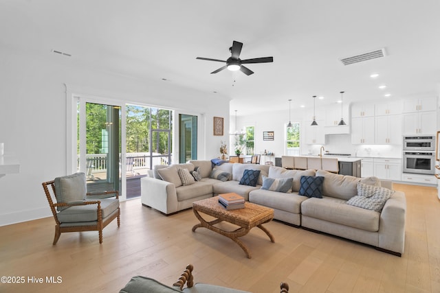 living room featuring a wealth of natural light, a ceiling fan, light wood-type flooring, and visible vents