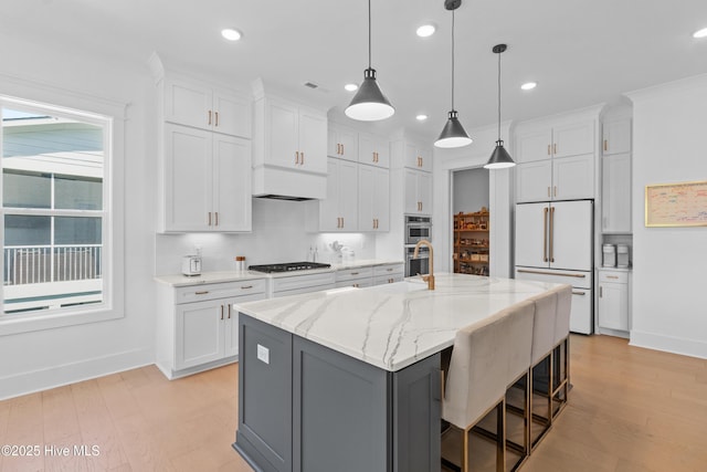 kitchen with high end fridge, stainless steel double oven, white cabinets, and gas cooktop