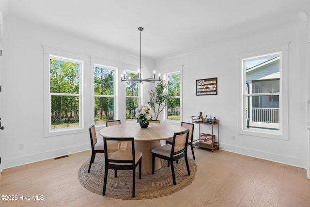 dining area featuring light wood-style floors, baseboards, visible vents, and a chandelier