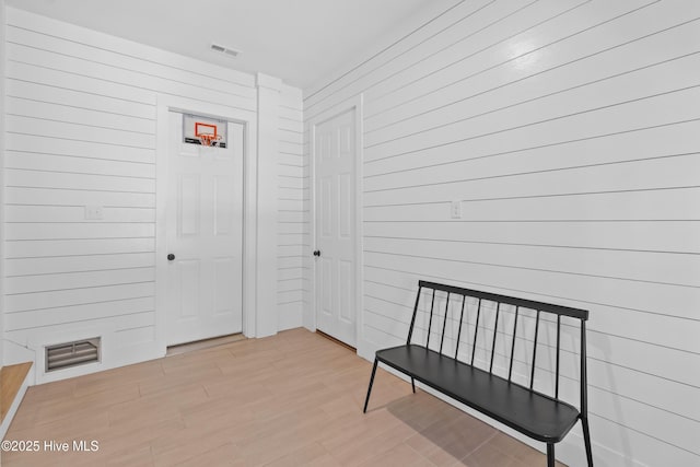 unfurnished room with visible vents, wood walls, and light wood-type flooring