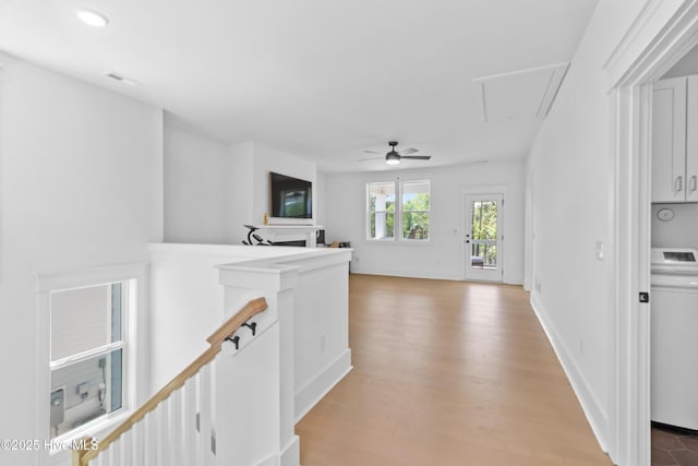 hall featuring light wood finished floors, attic access, washer / clothes dryer, an upstairs landing, and visible vents
