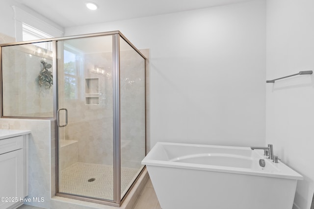 bathroom featuring a shower stall, a soaking tub, and vanity