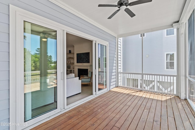 unfurnished sunroom with crown molding, ceiling fan, and hardwood / wood-style floors