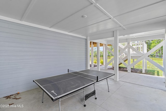 recreation room featuring concrete flooring and wood walls