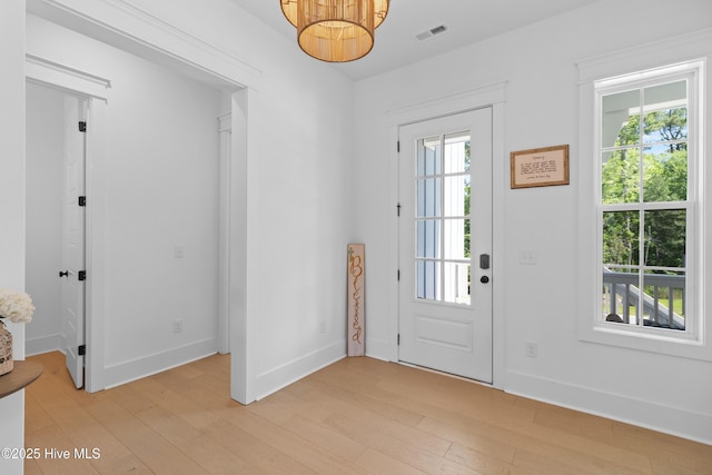 entrance foyer with baseboards, visible vents, light wood-style flooring, and an inviting chandelier