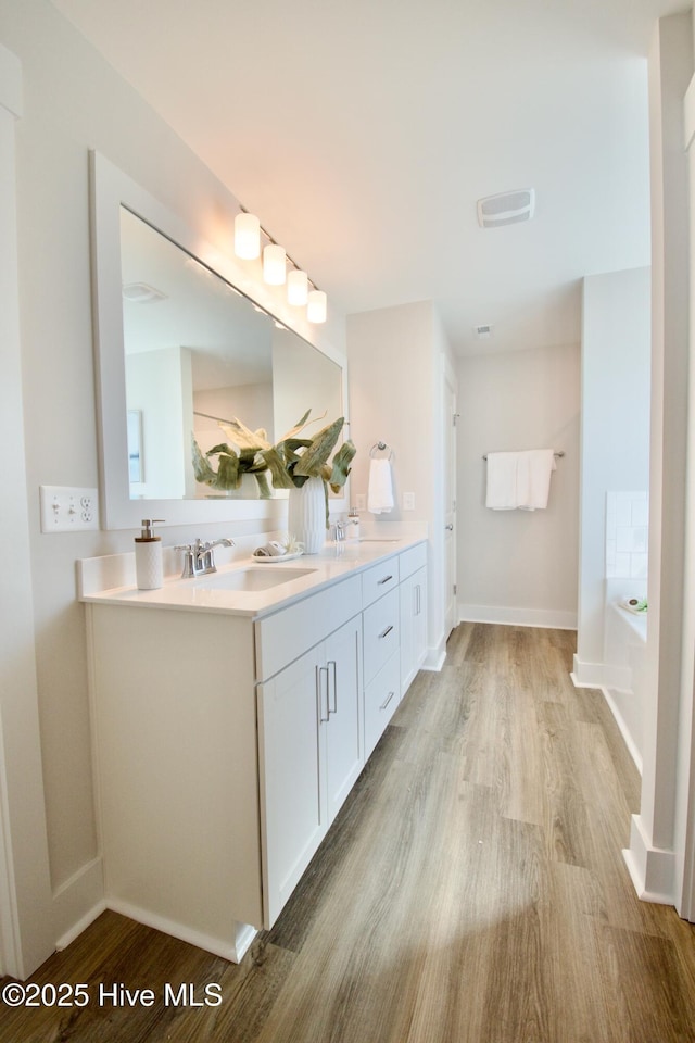218 Country Club Dr SW, Shallotte, NC 28470 - bathroom with double vanity, a sink, a garden tub, and wood finished floors