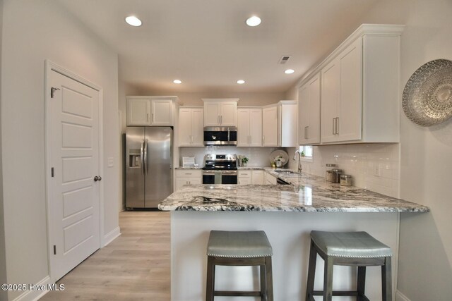 218 Country Club Dr SW, Shallotte, NC 28470 - kitchen featuring white cabinetry, appliances with stainless steel finishes, a sink, and light stone counters