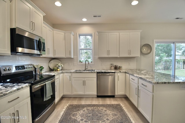 218 Country Club Dr SW, Shallotte, NC 28470 - kitchen with white cabinets, a sink, stainless steel appliances, a peninsula, and visible vents