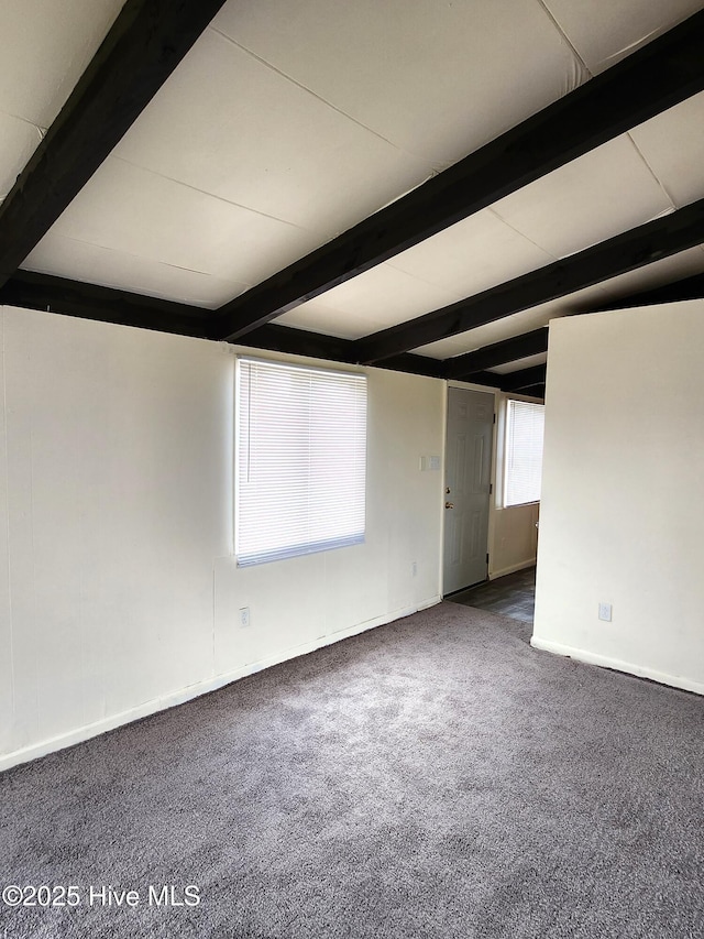 carpeted spare room featuring baseboards and beam ceiling