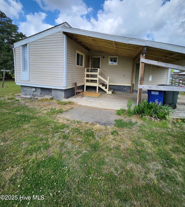 rear view of house featuring a lawn and an attached carport
