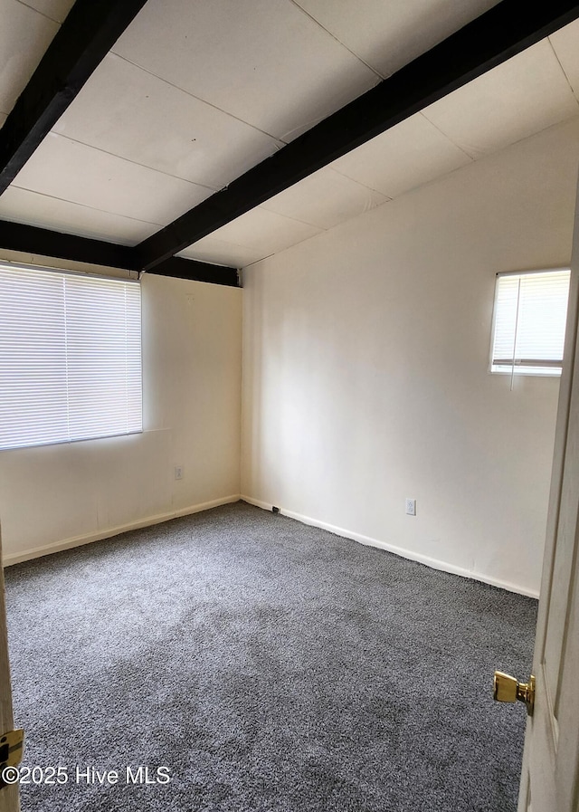 unfurnished room with baseboards, beamed ceiling, a wealth of natural light, and carpet