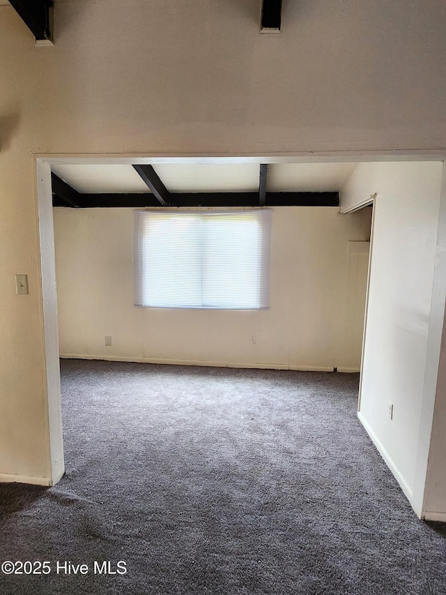 spare room with carpet flooring, baseboards, and beam ceiling