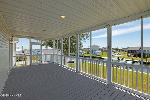 wooden terrace featuring a residential view, a water view, and a lawn