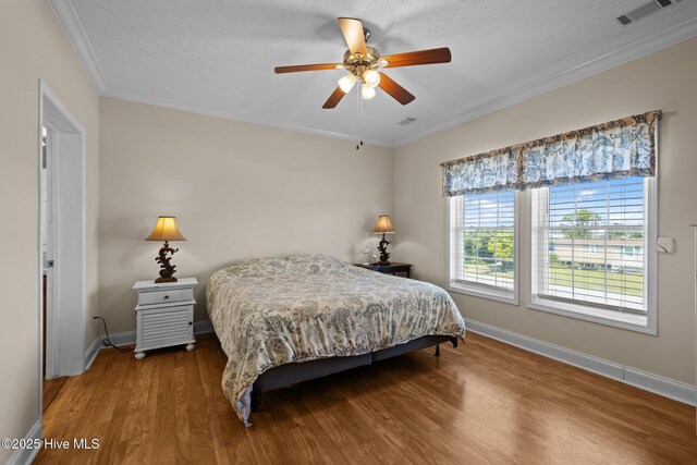 bedroom with wood finished floors, a textured ceiling, crown molding, baseboards, and ceiling fan