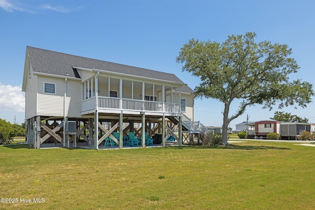 back of property featuring a lawn, stairway, a shingled roof, and covered porch