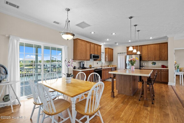dining space featuring crown molding, light wood-style floors, recessed lighting, and a textured ceiling