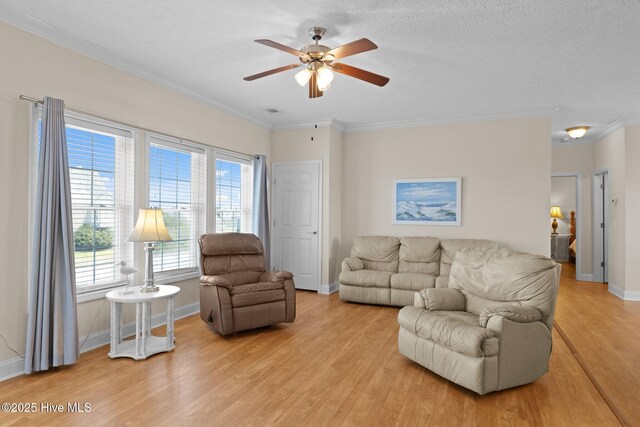 living room featuring light wood finished floors, a ceiling fan, baseboards, and ornamental molding