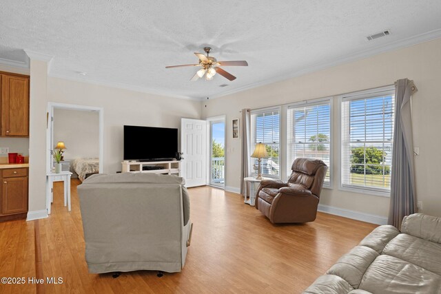 living area with a ceiling fan, light wood-style flooring, a textured ceiling, baseboards, and ornamental molding