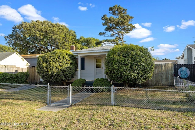 2205 Bay St, Morehead City, NC 28557 - view of property hidden behind natural elements with a chimney, a fenced front yard, a gate, and a front lawn