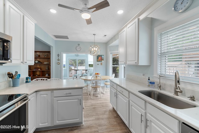 2403 W Oak Island Dr, Oak Island, NC 28465 - kitchen featuring stainless steel appliances, a peninsula, white cabinets, and a textured ceiling