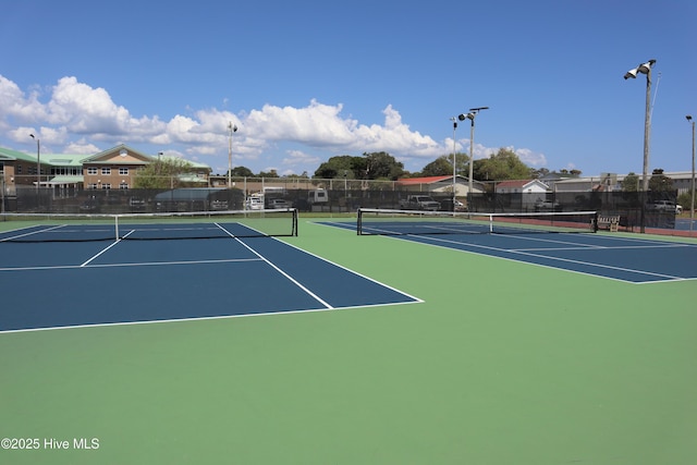 view of tennis court featuring fence and community basketball court