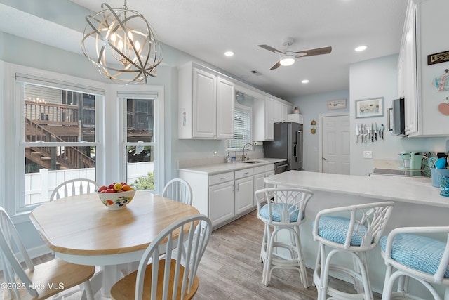 2403 W Oak Island Dr, Oak Island, NC 28465 - kitchen featuring a sink, stainless steel appliances, light countertops, white cabinetry, and light wood-style floors