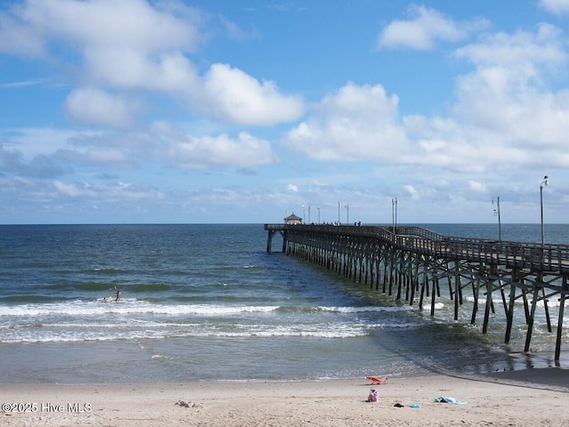 dock area featuring a pier, a water view, and a view of the beach