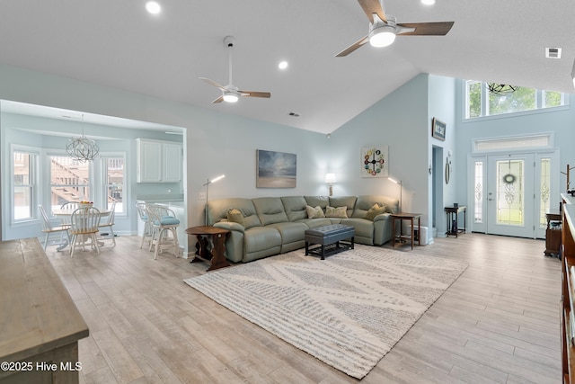 2403 W Oak Island Dr, Oak Island, NC 28465 - living room with a ceiling fan, a chandelier, light wood-style flooring, and high vaulted ceiling