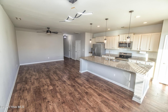 kitchen featuring a sink, baseboards, stainless steel appliances, and dark wood-type flooring