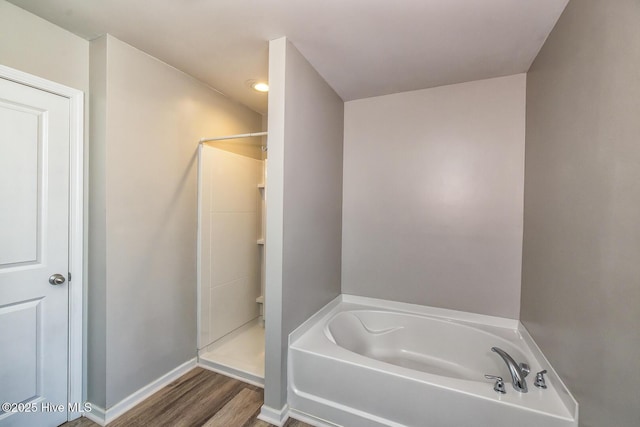 full bath featuring a garden tub, baseboards, walk in shower, and wood finished floors