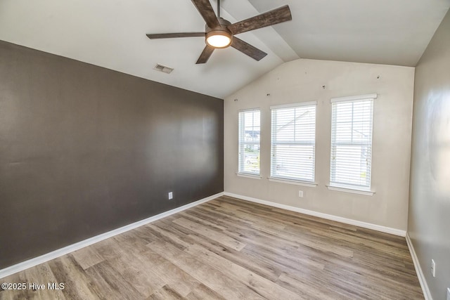 unfurnished room with ceiling fan, baseboards, wood finished floors, vaulted ceiling, and visible vents