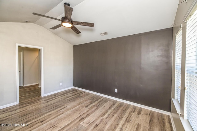 unfurnished room featuring a ceiling fan, visible vents, wood finished floors, baseboards, and lofted ceiling