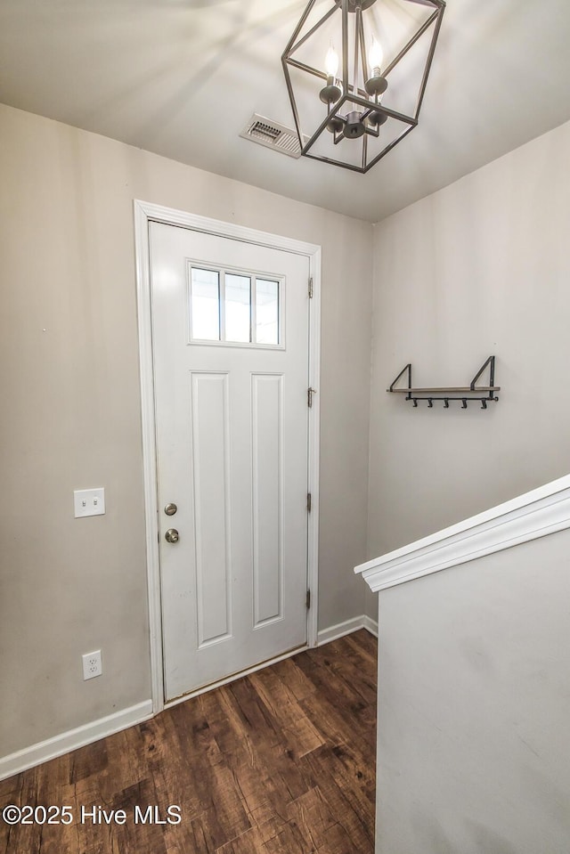 foyer featuring baseboards, wood finished floors, a notable chandelier, and visible vents