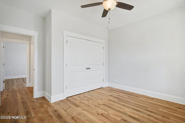 unfurnished bedroom featuring a closet, baseboards, ceiling fan, and light wood-style floors