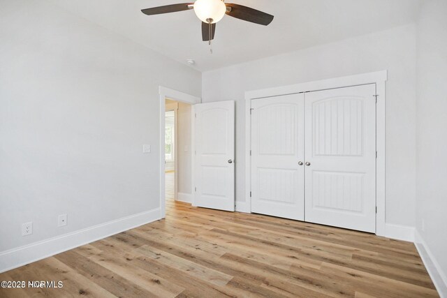unfurnished bedroom featuring a closet, baseboards, a ceiling fan, and light wood-type flooring