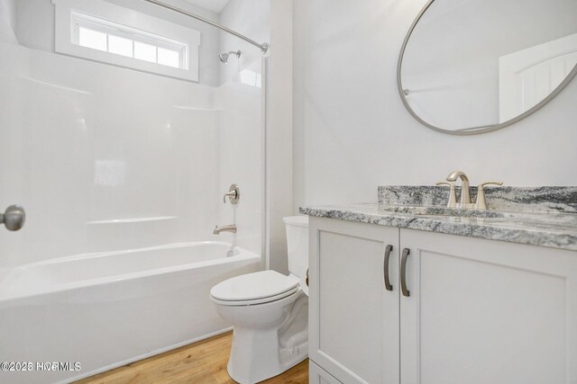 bathroom featuring toilet, bathtub / shower combination, wood finished floors, and vanity