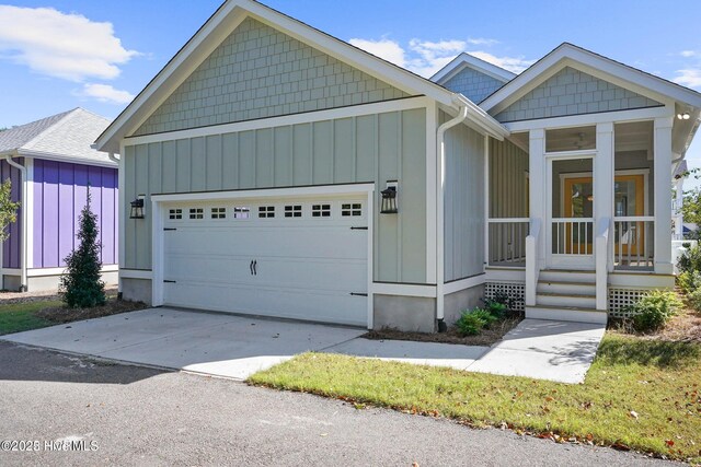 view of front of house featuring board and batten siding, driveway, covered porch, and a garage